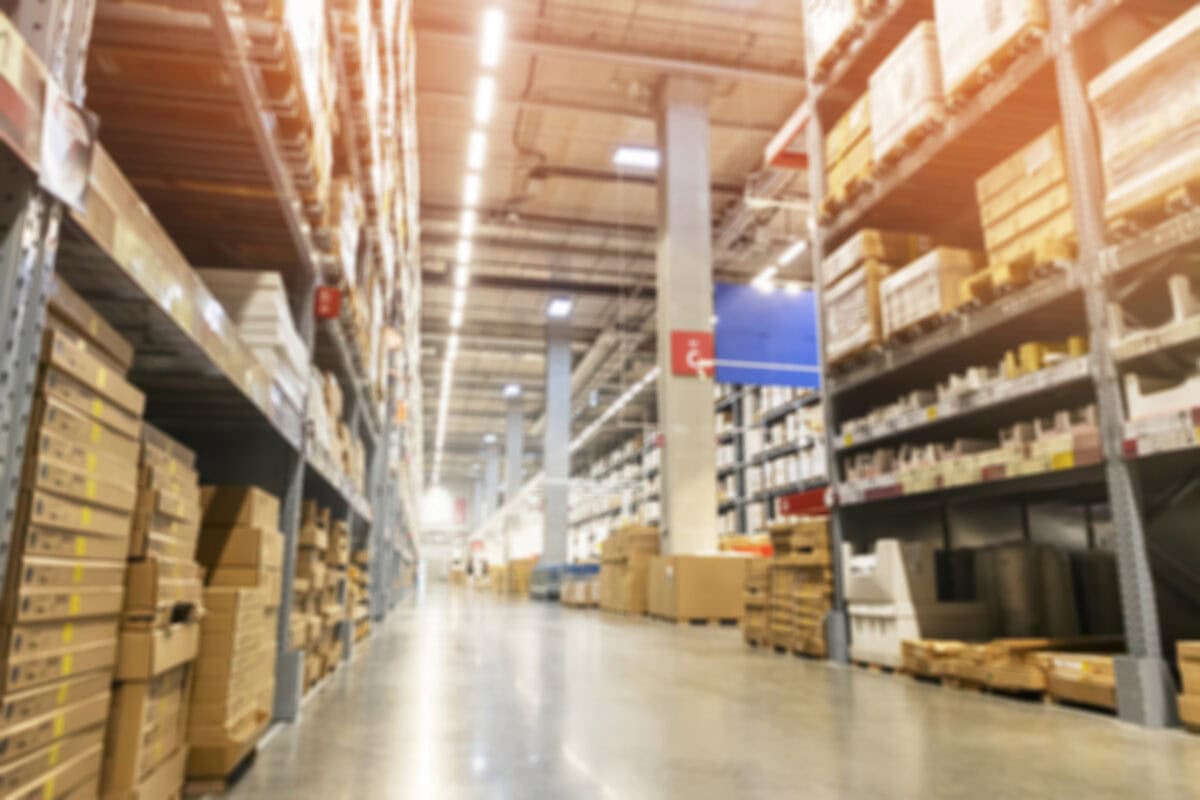 A blurred image of a warehouse full of empty cardboard boxes stacked on the shelves.